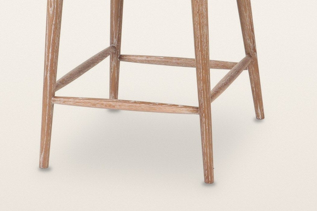 Close-up of the Morrovalle base: four round tapered ash legs in a weathered finish joined by a box of four footrest rails