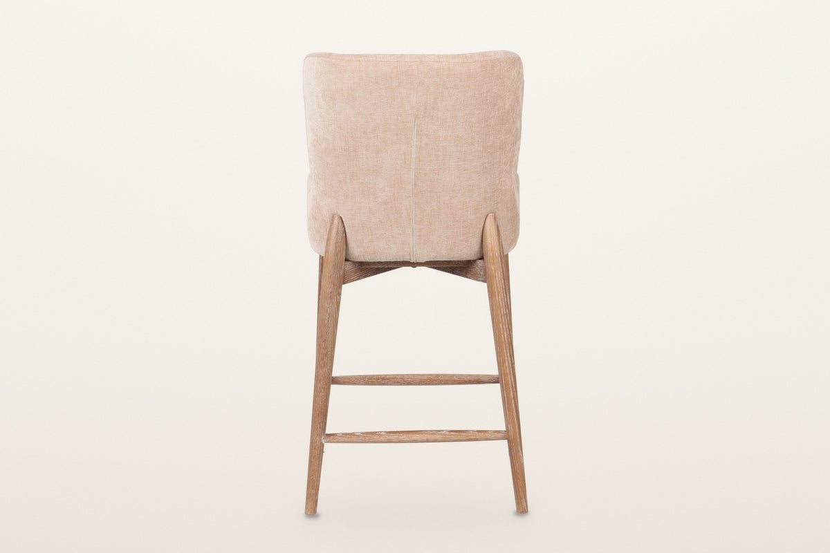 Morrovalle counter stool in Champagne Chenille from behind on a warm white studio backdrop: a plain upholstered back with one