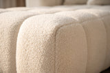Close-up of the white boucle on the Nembo Boucle Cloud Sectional: curly loops over a rounded front edge and a deep seam between two wide channels