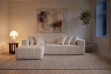 Nembo Boucle Cloud Sectional in the same Copenhagen living room at night, the paper table lamp lit and the window dark