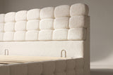 Close-up of the cream bouclé headboard blocks, the plain band below and its two small metal loops