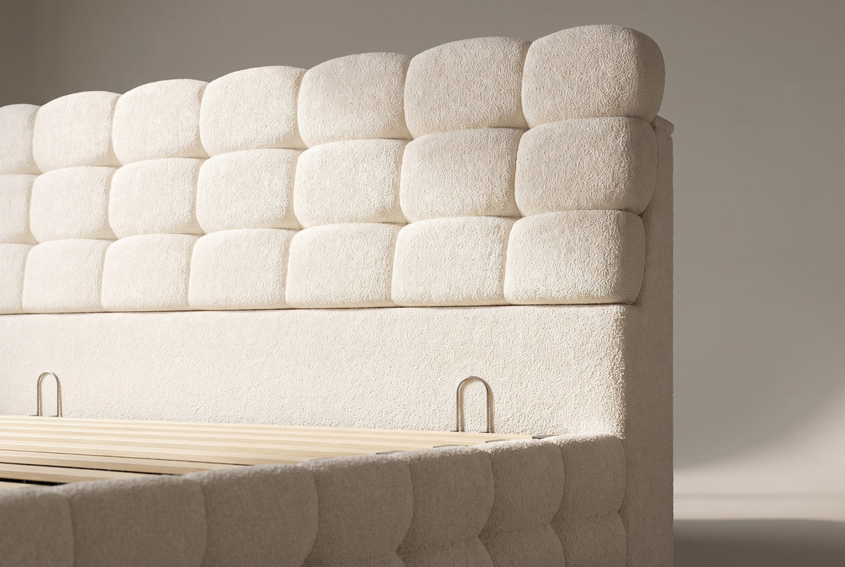 Close-up of the cream bouclé headboard blocks, the plain band below and its two small metal loops