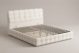 Nemi storage bed in cream white bouclé, three-quarter view of the bare frame with slats on a warm grey studio backdrop