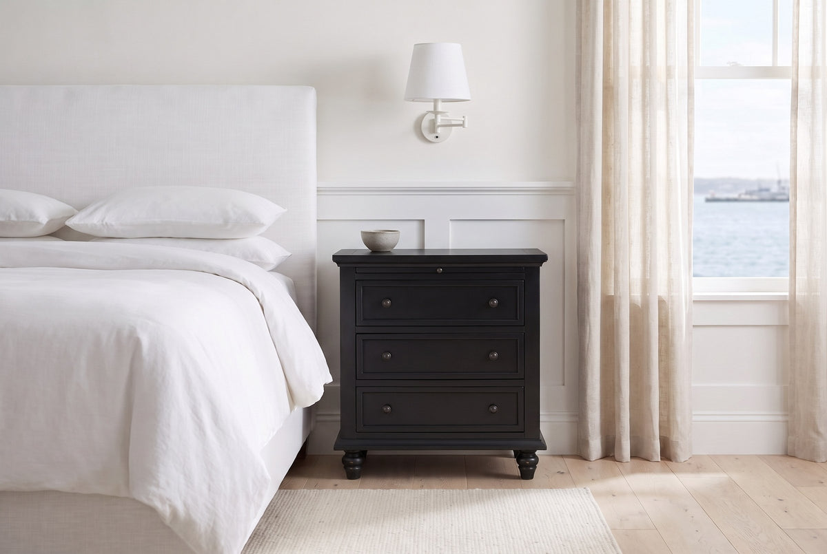 Nervi nightstand in Black beside a bed with white linen in a bright Halifax bedroom with a harbour view