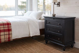 Nervi nightstand in Black beside a bed with white linen in a whitewashed Muskoka cottage bedroom by the lake