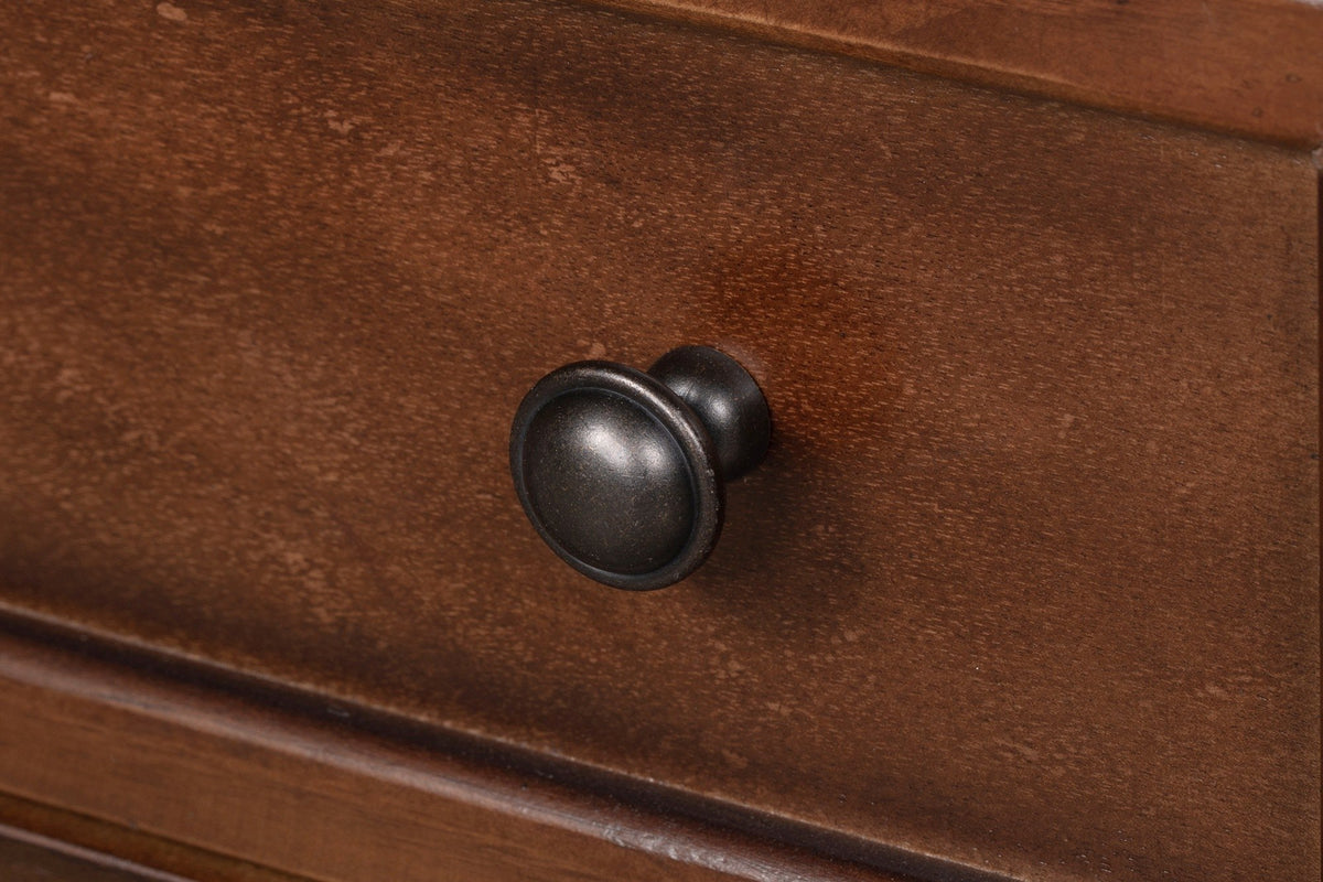 Close-up of a Nervi drawer front: the moulded frame, the wood grain and a round dark-bronze knob