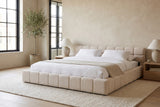 Noto bed made up with white linen in a Montreal loft bedroom with plaster walls, black steel windows and an olive tree