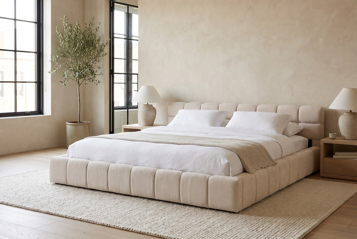 Noto bed made up with white linen in a Montreal loft bedroom with plaster walls, black steel windows and an olive tree