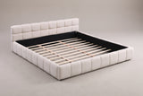 Noto tufted chenille platform bed in beige, three-quarter view on a warm grey studio backdrop with the wood slats showing