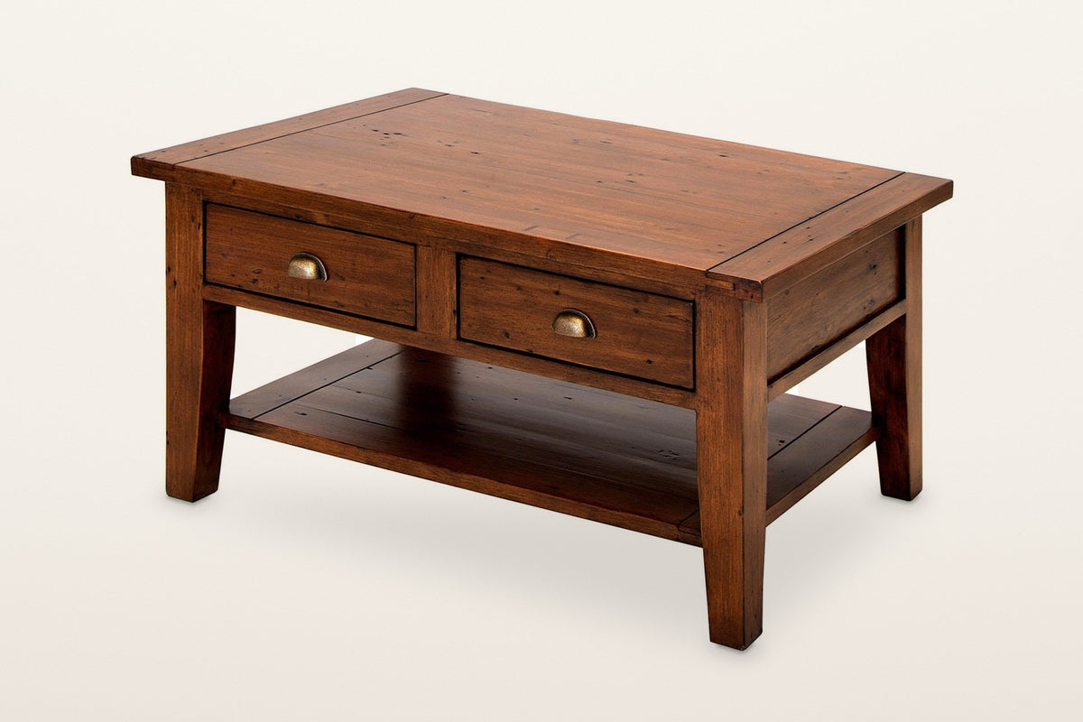 Novella coffee table in African Dusk reclaimed pine: two drawers with brass cup pulls and a low open shelf, three-quarter view on a warm white studio backdrop