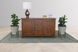 Novella sideboard styled with a table lamp between two potted plants on a blue rug