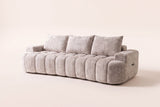 The Nuvola sofa in Camel, front three-quarter view: a long, low channel-tufted boucle sofa with a softly curved front, low arms and three back pillows, on an off-white studio background