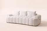 The Nuvola sofa in White, front three-quarter view: ivory boucle with vertical channels and a softly curved front, on an off-white studio background