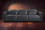 The Octavia 3 seat in Aged Slate distressed full leather on a dark herringbone floor, seen from the front, headrests down. Shown in Aged Slate, 3 seat.