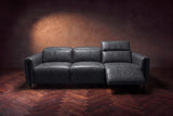 The Octavia 3 seat in Aged Slate distressed full leather on a dark herringbone floor, seen from the front, the right recliner open and its headrest raised. Shown in Aged Slate, 3 seat.