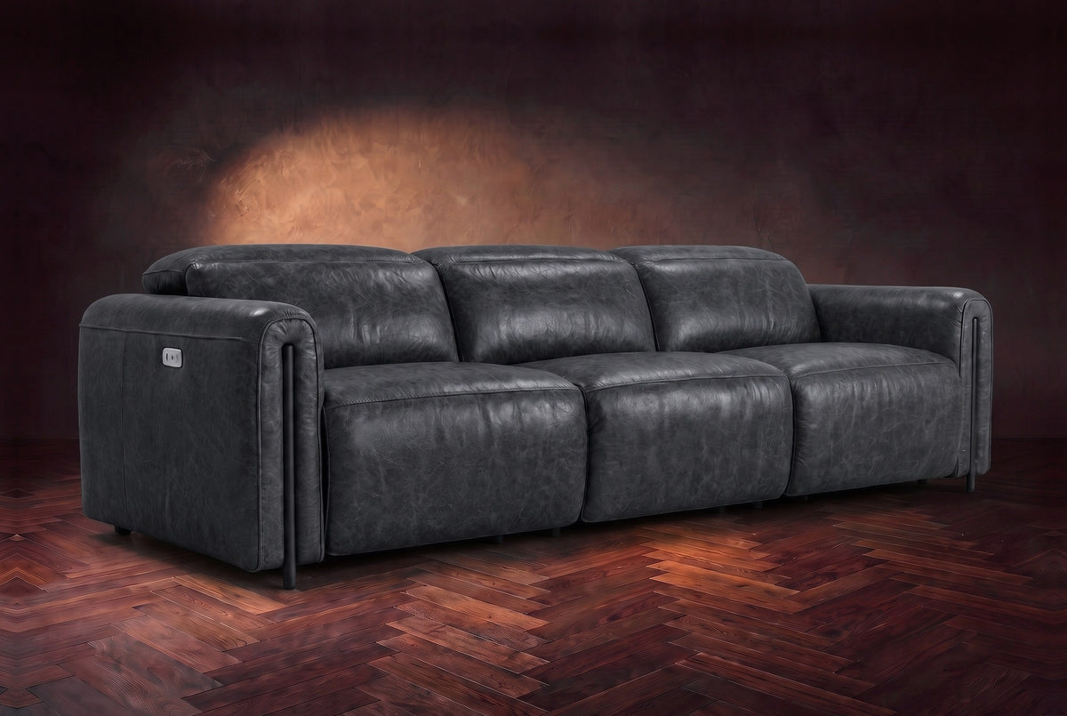 The Octavia 3 seat in Aged Slate distressed full leather on a dark herringbone floor, headrests down and footrests closed. Shown in Aged Slate, 3 seat.
