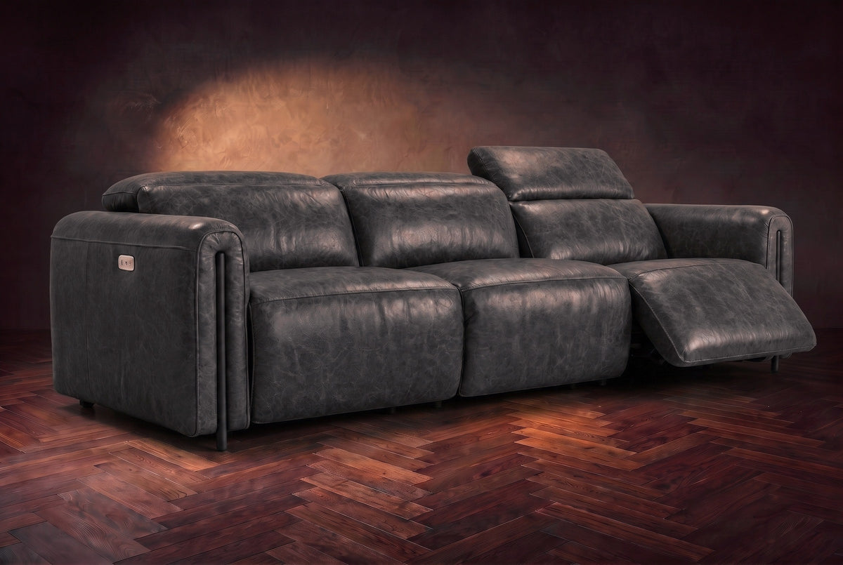 The Octavia 3 seat in Aged Slate distressed full leather on a dark herringbone floor, the right recliner open and its headrest raised. Shown in Aged Slate, 3 seat.