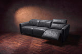 The Octavia 3 seat in Aged Slate distressed full leather on a dark herringbone floor, seen from the right, the right recliner open and its headrest raised. Shown in Aged Slate, 3 seat.