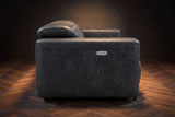 The Octavia loveseat in Aged Slate distressed full leather on a dark herringbone floor, seen from the side, the arm with its control panel and a raised headrest. Shown in Aged Slate, Loveseat.