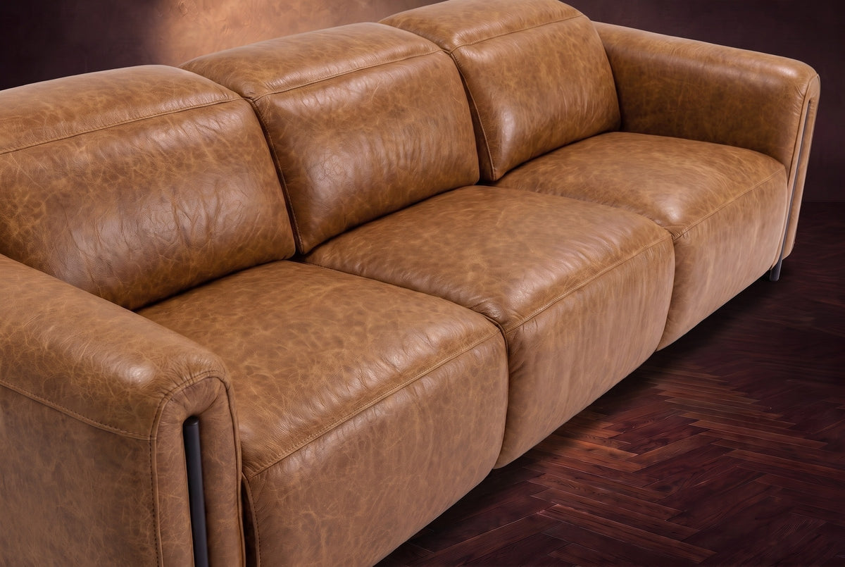 The Octavia 3 seat in Antiqued Caramel distressed full leather on a dark herringbone floor, seen close from above, the seats and backs. Shown in Antiqued Caramel, 3 seat.