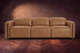 The Octavia 3 seat in Antiqued Caramel distressed full leather on a dark herringbone floor, seen from the front, headrests down. Shown in Antiqued Caramel, 3 seat.
