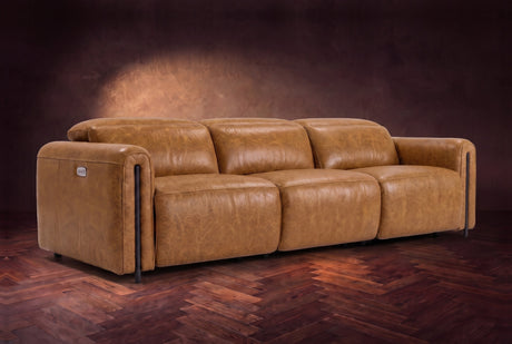 The Octavia 3 seat in Antiqued Caramel distressed full leather on a dark herringbone floor, headrests down and footrests closed. Shown in Antiqued Caramel, 3 seat.