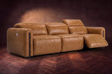 The Octavia 3 seat in Antiqued Caramel distressed full leather on a dark herringbone floor, the right recliner open and its headrest raised. Shown in Antiqued Caramel, 3 seat.