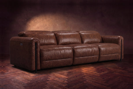 The Octavia 3 seat in Burnished Chestnut distressed full leather on a dark herringbone floor, headrests down and footrests closed. Shown in Burnished Chestnut, 3 seat.