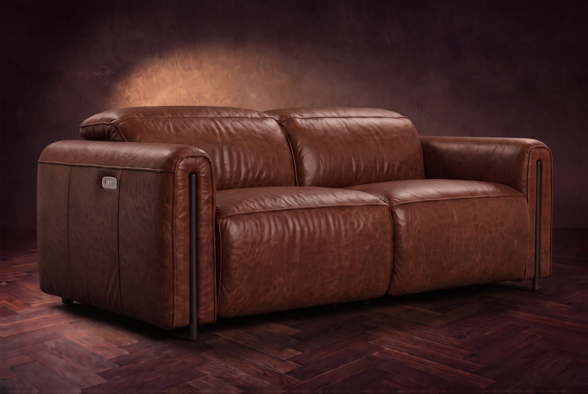The Octavia loveseat in Burnished Chestnut distressed full leather on a dark herringbone floor, headrests down and footrests closed. Shown in Burnished Chestnut, Loveseat.