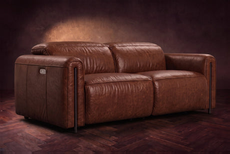 The Octavia loveseat in Burnished Chestnut distressed full leather on a dark herringbone floor, headrests down and footrests closed. Shown in Burnished Chestnut, Loveseat.