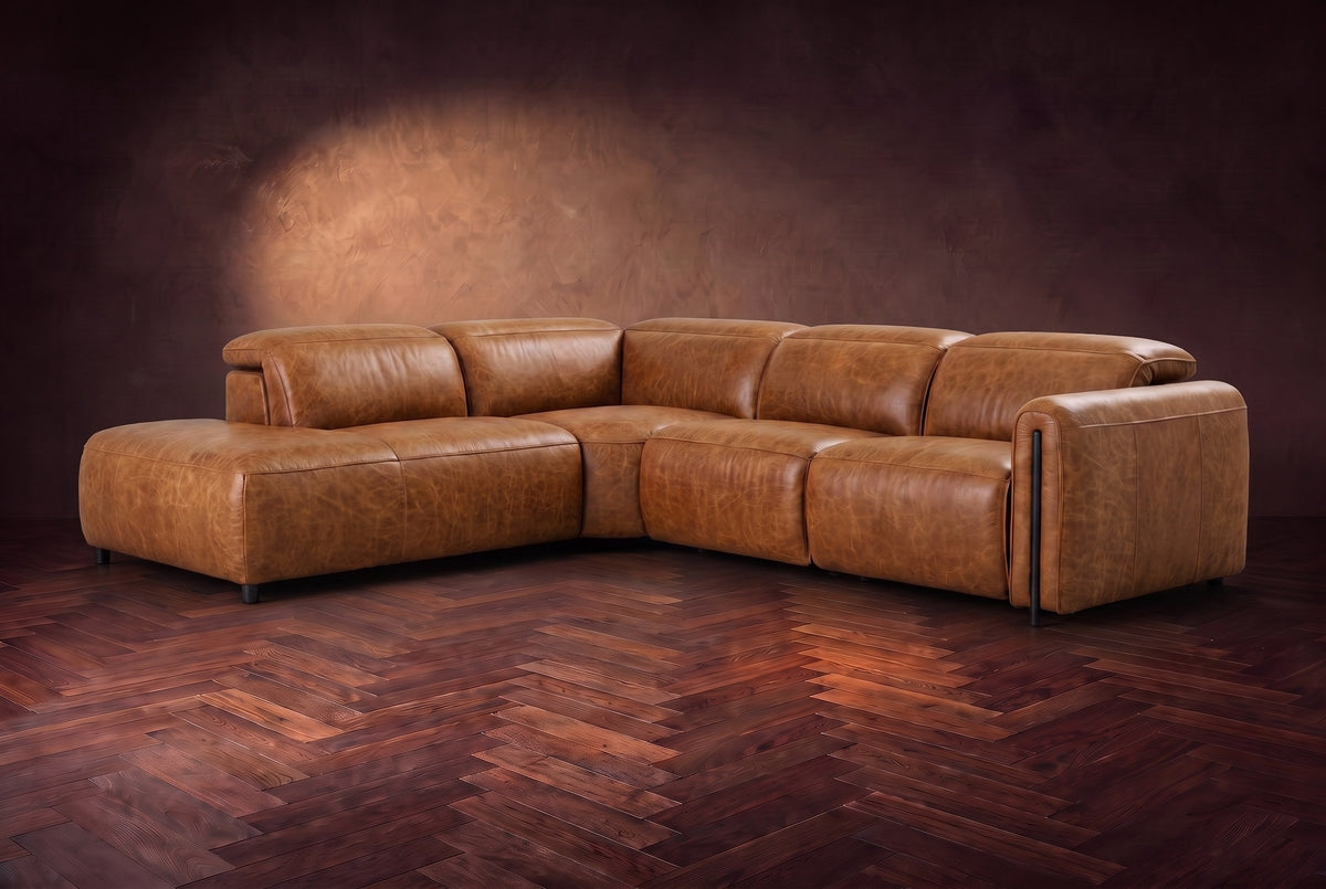 Octavia sectional in Antiqued Caramel on a walnut herringbone floor, three-quarter view, headrests down and footrests closed, Left bumper.