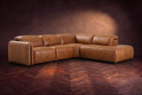 Octavia sectional in Antiqued Caramel on a walnut herringbone floor, three-quarter view, headrests down and footrests closed, Right bumper.