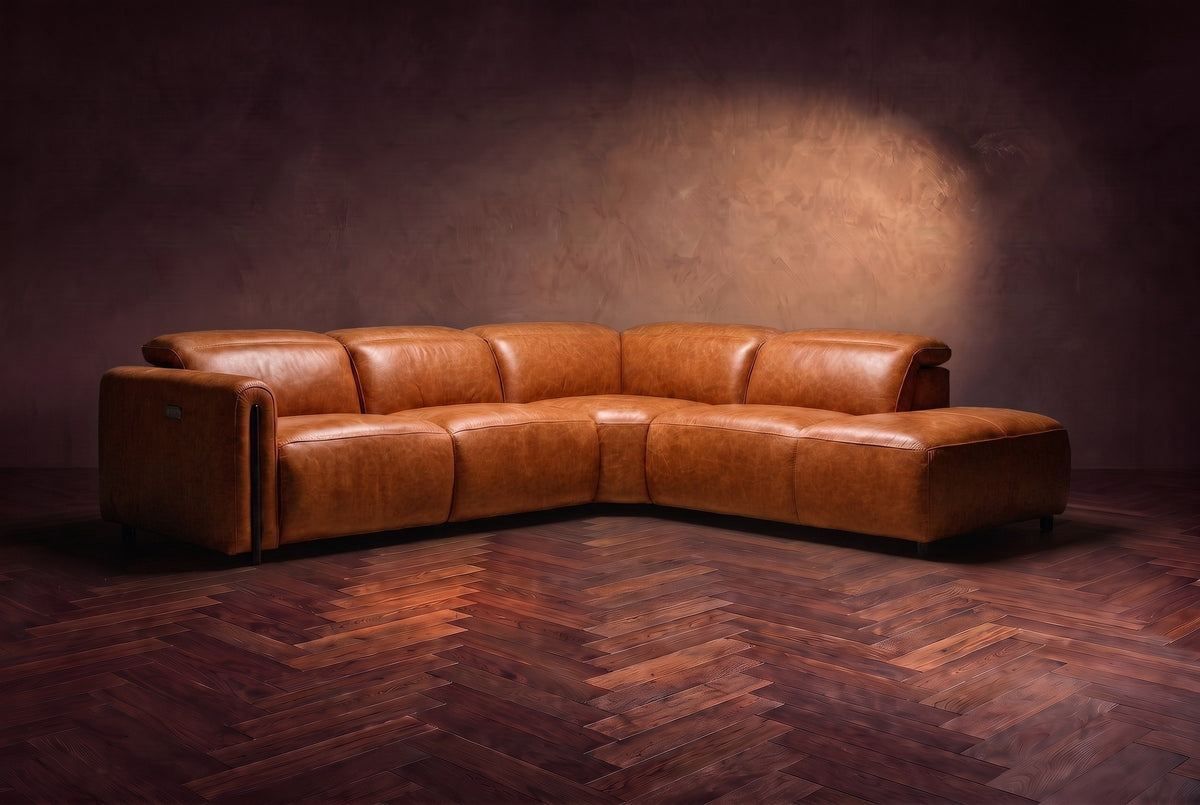 Octavia sectional in Tuscan Cognac on a walnut herringbone floor, low three-quarter view from further back, footrests closed, Right bumper.