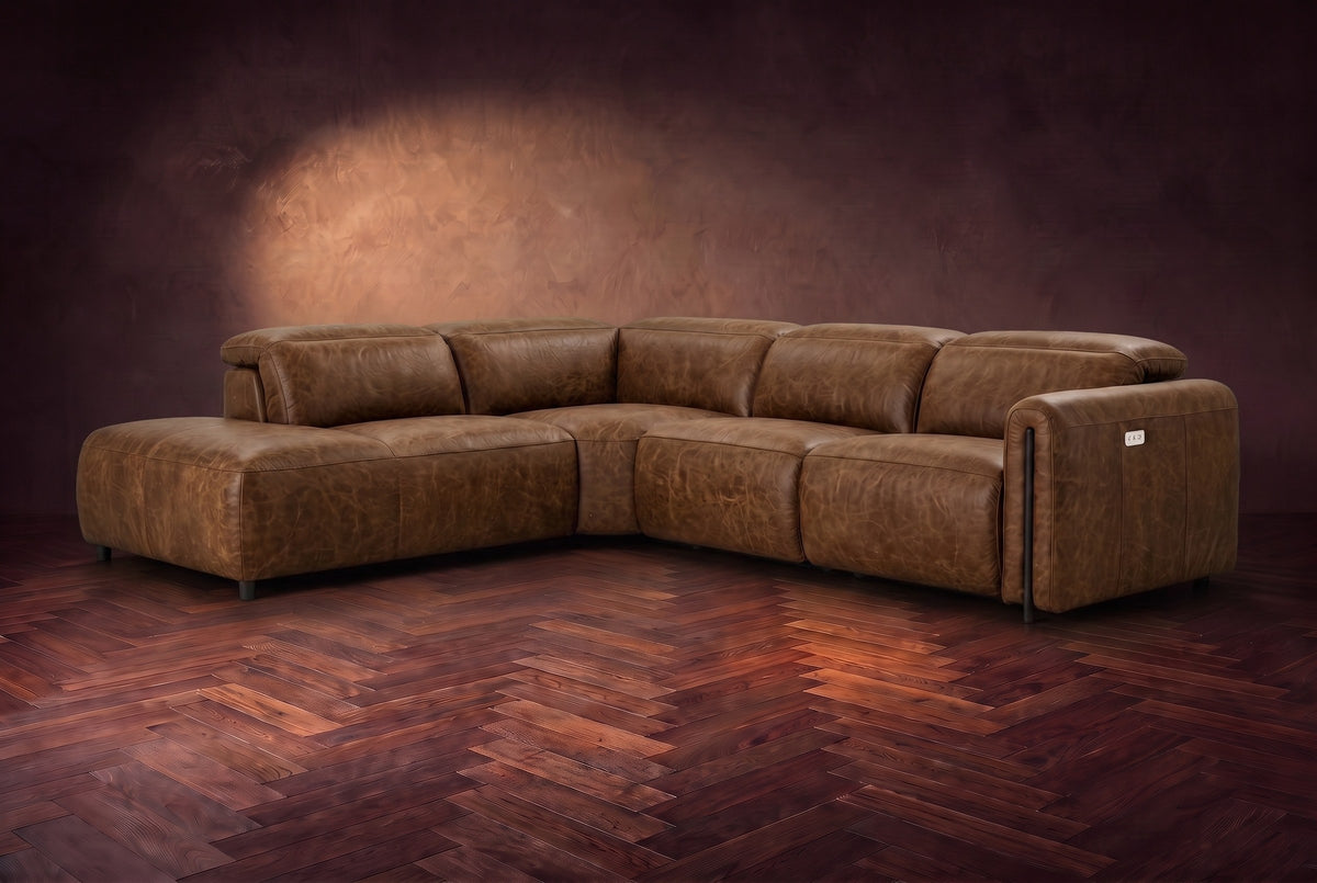 Octavia sectional in Weathered Saddle on a walnut herringbone floor, three-quarter view, headrests down and footrests closed, Left bumper.