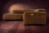 Octavia sectional in Weathered Saddle on a walnut herringbone floor, seen from the arm end, footrests closed, Left bumper.
