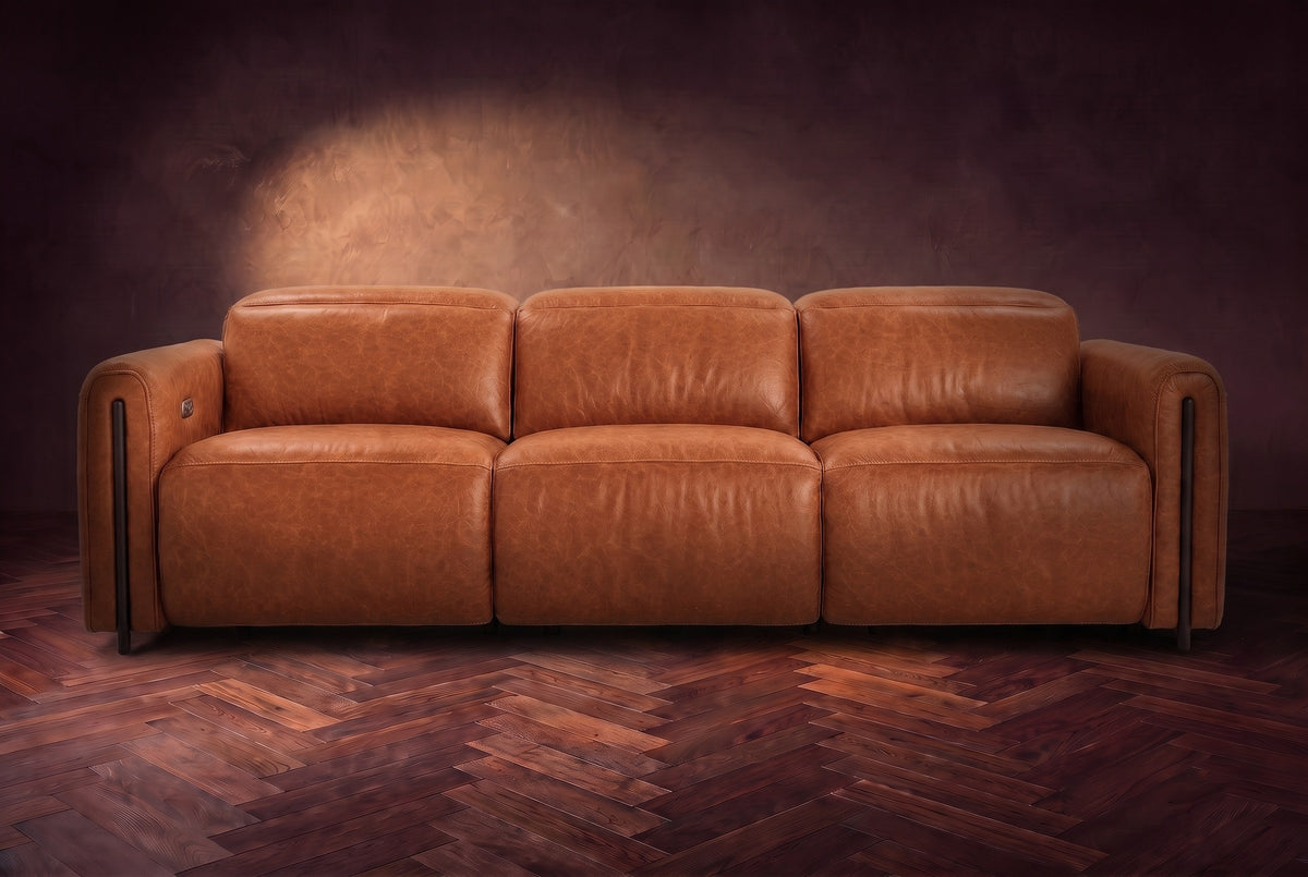 The Octavia 3 seat in Tuscan Cognac distressed full leather on a dark herringbone floor, seen from the front, headrests down. Shown in Tuscan Cognac, 3 seat.