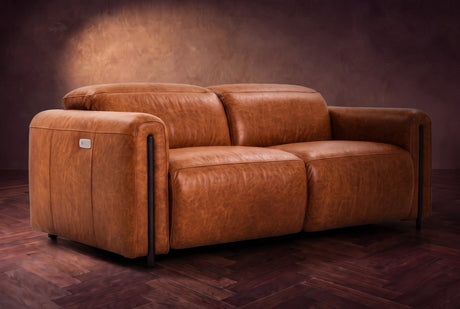 The Octavia loveseat in Tuscan Cognac distressed full leather on a dark herringbone floor, headrests down and footrests closed. Shown in Tuscan Cognac, Loveseat.