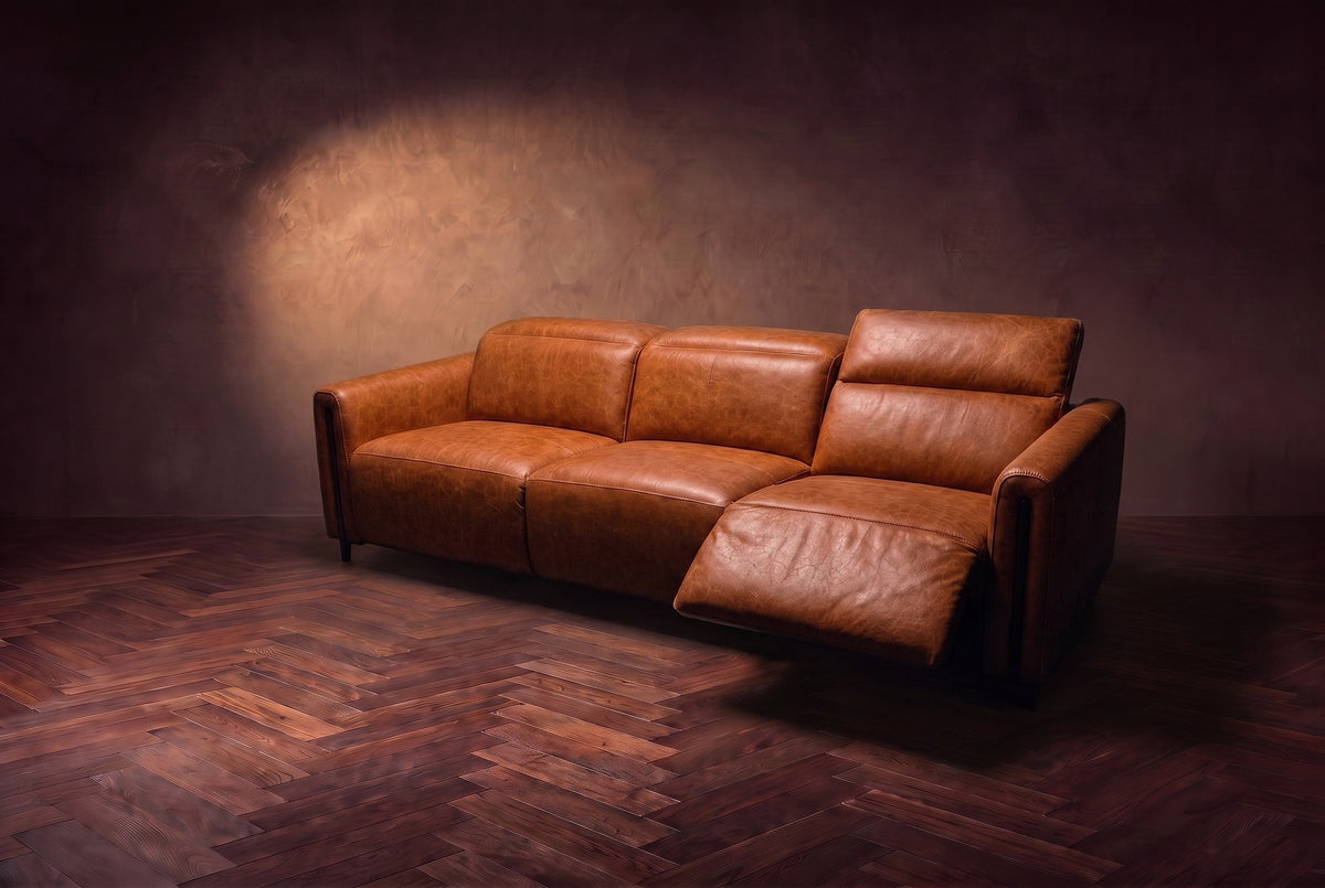 The Octavia 3 seat in Tuscan Cognac distressed full leather on a dark herringbone floor, seen from the right, the right recliner open and its headrest raised. Shown in Tuscan Cognac, 3 seat.