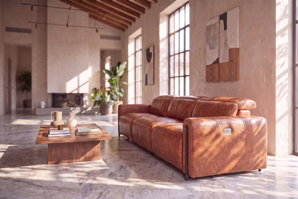 The Octavia 3 seat seen from its right end in a sunlit plaster room with a timber ceiling and a marble floor, the near headrest raised. Shown in Tuscan Cognac, 3 seat.
