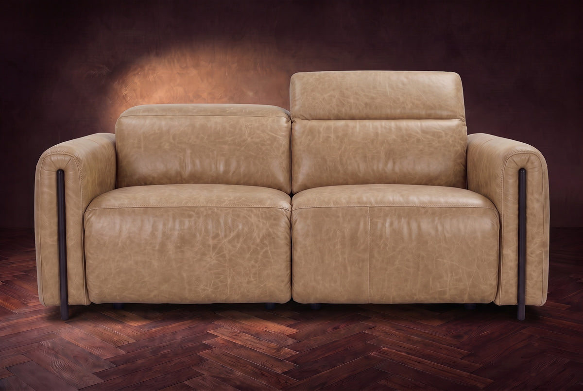 The Octavia loveseat in Washed Sand distressed full leather on a dark herringbone floor, seen from the front, the right headrest raised. Shown in Washed Sand, Loveseat.