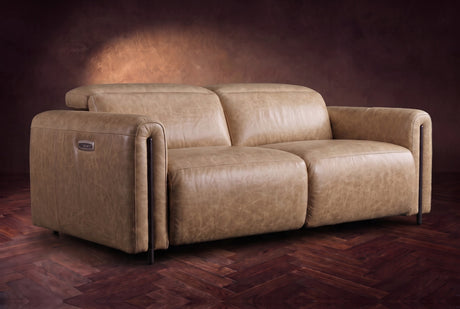 The Octavia loveseat in Washed Sand distressed full leather on a dark herringbone floor, headrests down and footrests closed. Shown in Washed Sand, Loveseat.