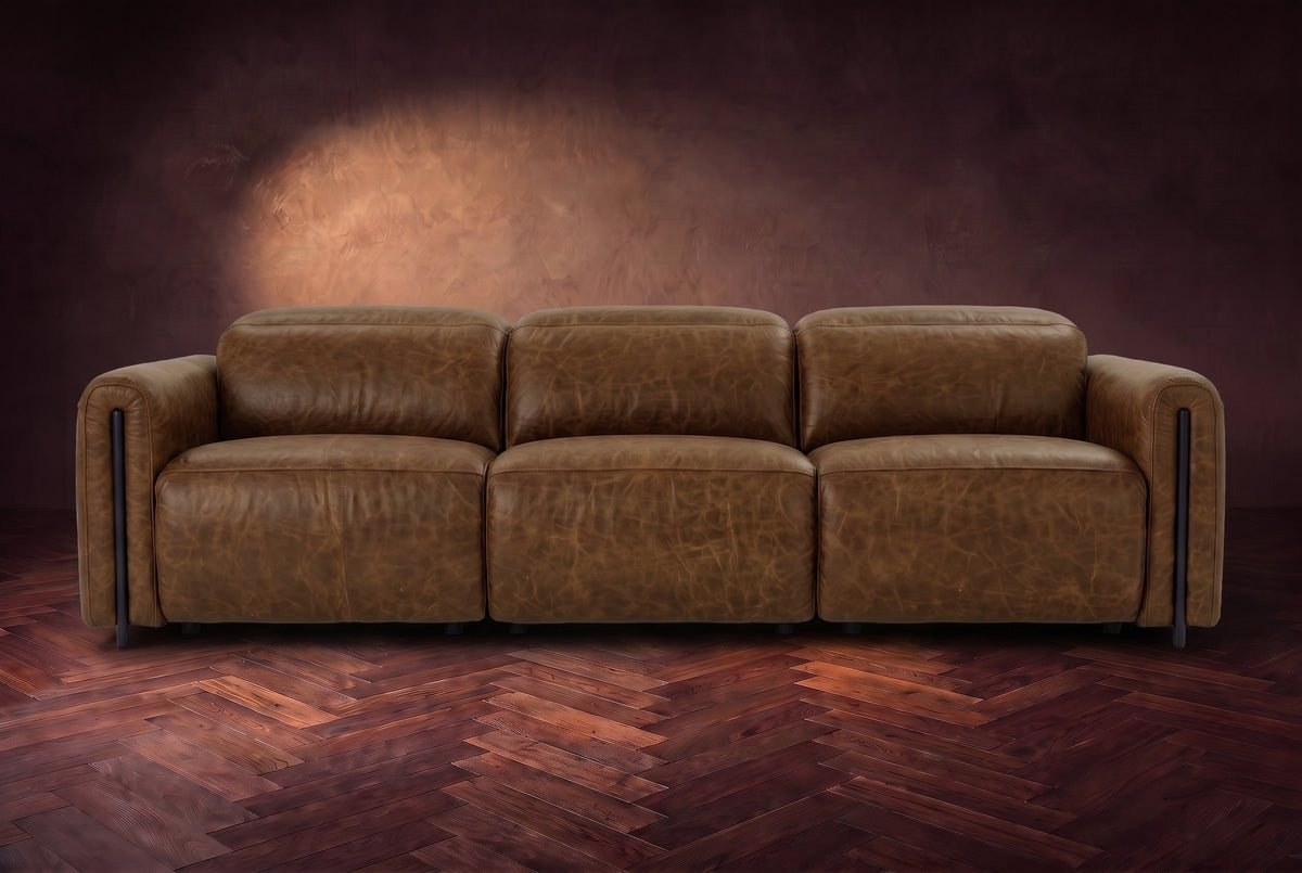 The Octavia 3 seat in Weathered Saddle distressed full leather on a dark herringbone floor, seen from the front, headrests down. Shown in Weathered Saddle, 3 seat.