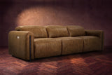 The Octavia 3 seat in Weathered Saddle distressed full leather on a dark herringbone floor, headrests down and footrests closed. Shown in Weathered Saddle, 3 seat.