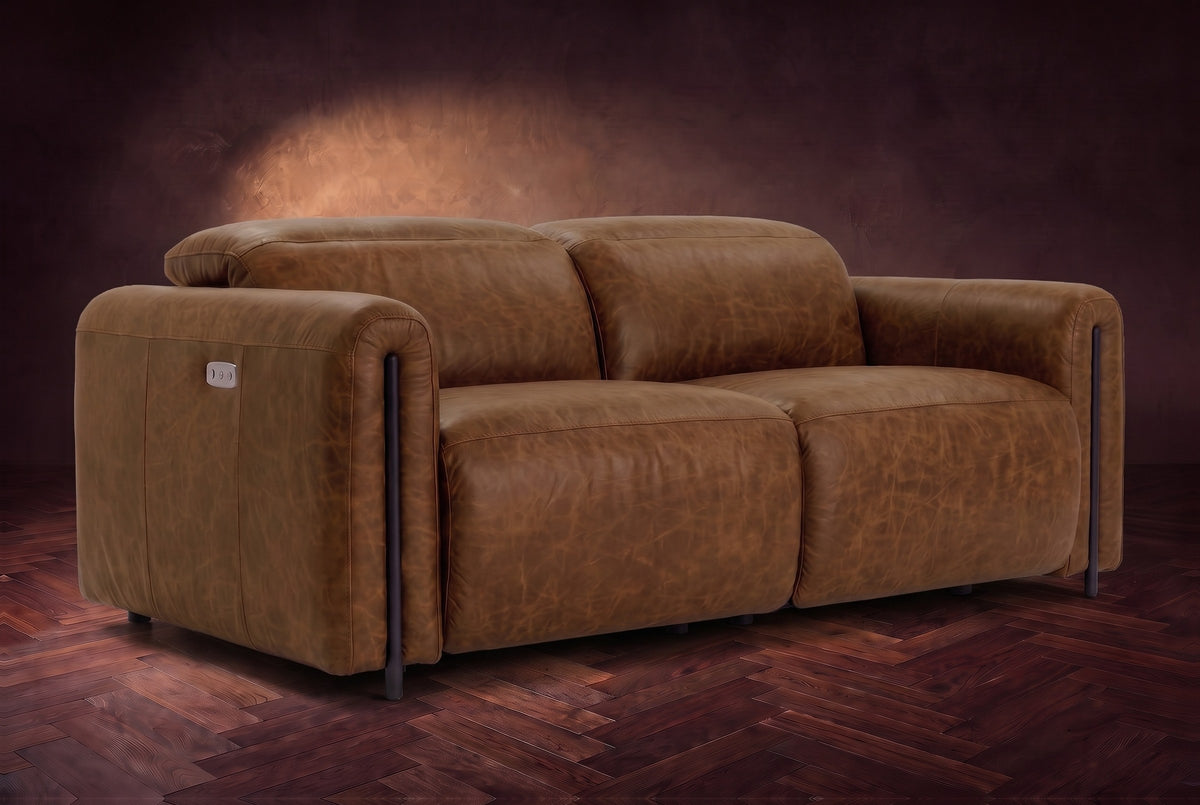 The Octavia loveseat in Weathered Saddle distressed full leather on a dark herringbone floor, headrests down and footrests closed. Shown in Weathered Saddle, Loveseat.