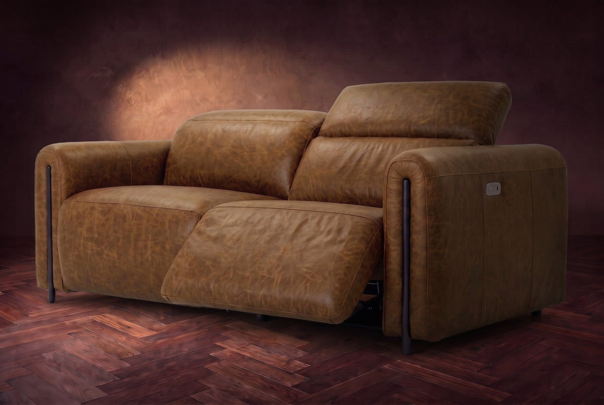 The Octavia loveseat in Weathered Saddle distressed full leather on a dark herringbone floor, seen from the right, the right recliner open and its headrest raised. Shown in Weathered Saddle, Loveseat.
