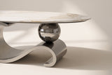 Close-up of the Gray Ondina coffee table's base: the polished sphere resting on the gray steel ribbon, and the scroll at its end