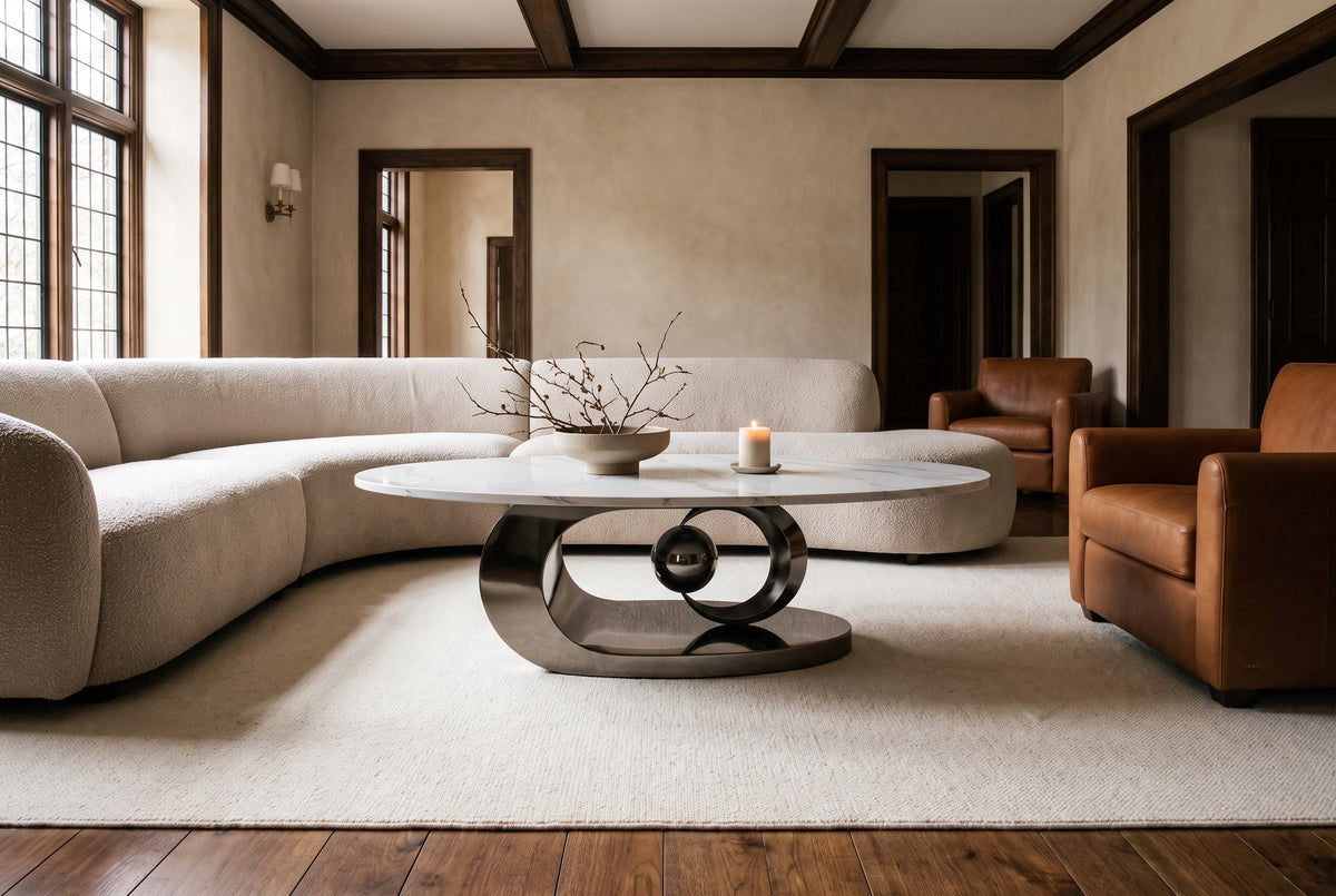 The Oriana coffee table in Gray on an ivory wool rug between an oatmeal boucle sofa and two cognac leather club chairs, in a beamed plaster living room with walnut floors