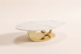 The Oriana coffee table seen from a low side angle, showing the slim stone edge and the gold ring and sphere beneath it, on an off-white studio background