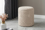 Orla beige sculpted cotton ottoman on a grey floor beside a dark curtain