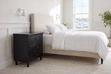 Ortona nightstand in Black beside a bed with white linen in a bright Halifax bedroom with a harbour view